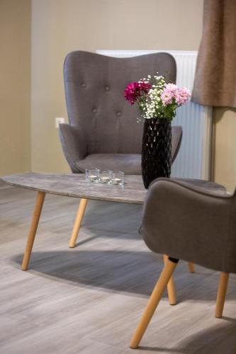 a vase of flowers sitting on a coffee table next to a chair at Cavallari Palace Hotel Suites in Athens