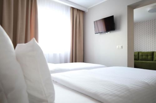 a hotel room with two beds and a television on the wall at Citi Hotel's Warszawa-Falenty in Raszyn