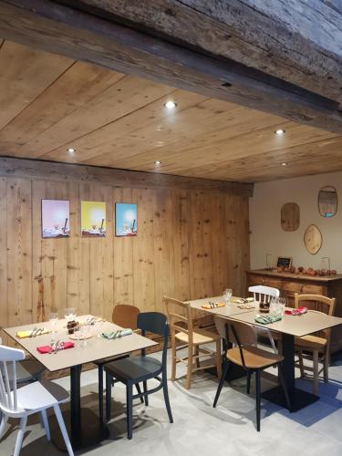 une salle à manger avec des murs en bois, des tables et des chaises dans l'établissement Aux fermes de la Croix, Maison d'hôtes, Spa, à Hauteluce