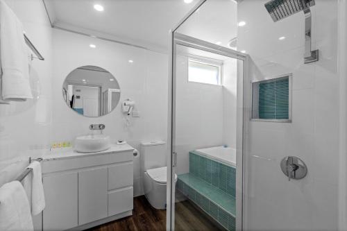 La salle de bains blanche est pourvue d'un lavabo et d'un miroir. dans l'établissement Rosebud Motel, à Tootgarook