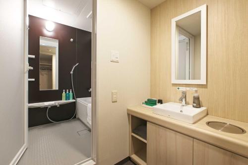 a bathroom with a sink and a toilet and a mirror at Hotel Route Inn Choshi Eki Nishi in Choshi
