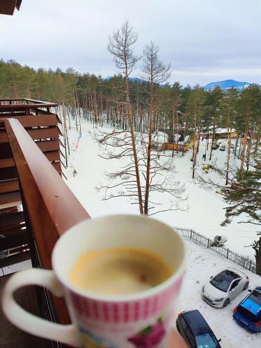 a cup of coffee sitting on a table with a snow covered yard at BalkanHill2 S37 Pekovic green in Zlatibor