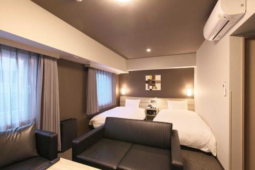 um quarto de hotel com duas camas e um sofá em Hotel Route Inn Choshi Eki Nishi em Choshi
