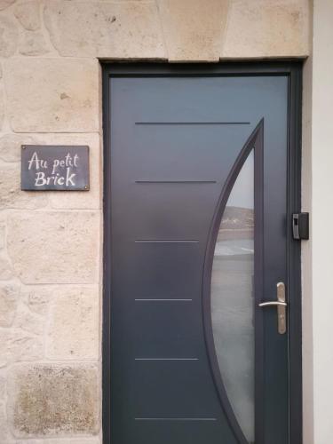 a blue door with a sign on a brick wall at Au Petit Brick - Cosy beachfront house in Maupertus-sur-Mer