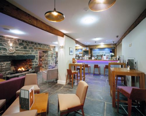 a restaurant with tables and chairs and a fireplace at Cross Foxes - Bar Grill Rooms in Dolgellau