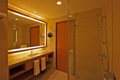 a bathroom with a shower and a sink and a mirror at Shangri-La Serviced Apartments, Yangon in Yangon