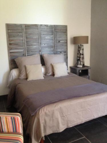 une chambre avec un grand lit avec une tête de lit dans l'établissement Gite au coeur de la Provence & SPA, à Saint-Cannat