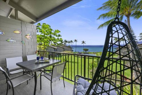 a table and chairs on a balcony with a view of the ocean at Oceanside-Spectacular View and Poolside Oasis in Kahana
