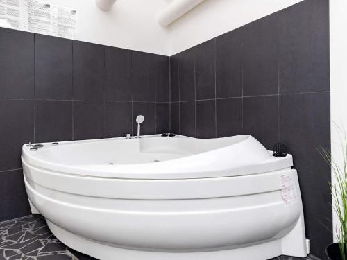 a white bath tub in a bathroom with black tiles at 6 person holiday home in Otterup in Otterup