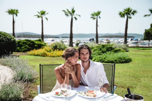 a bride and groom sitting at a table with food at Ilirija Resort Hotel Ilirija in Biograd na Moru