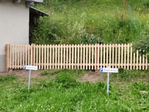 two signs in front of a wooden fence at Sonniges Chalet Arosa für 6 Pers alleinstehend mit traumhaftem Bergpanorama in Langwies
