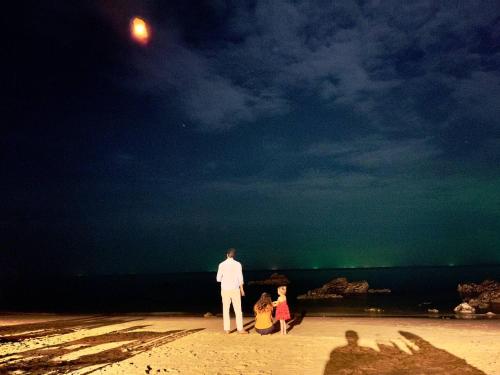 a man and two children standing on a beach at night at Kohjum Seafront Resort in Ko Jum