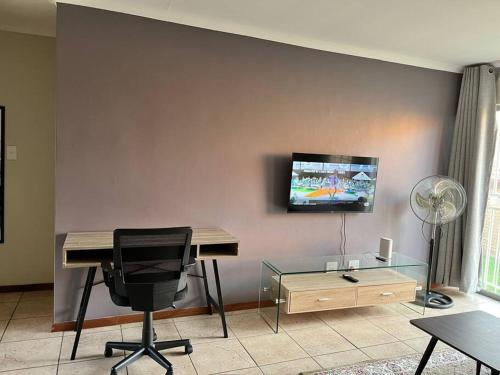 a desk and a chair in a room with a television at The Reeds: 2 Bedroom townhouse in Centurion