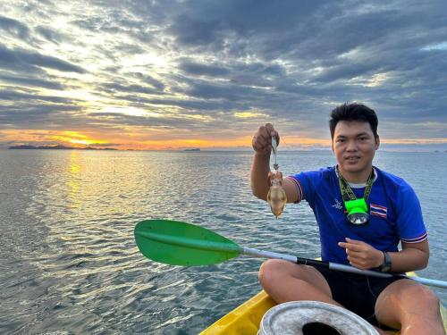 a man is sitting on a boat with a paddle at Kohjum Seafront Resort in Ko Jum