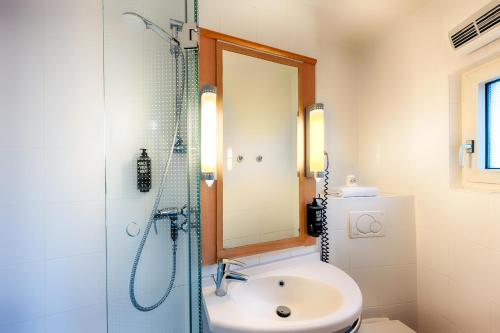 W łazience znajduje się umywalka oraz prysznic z lustrem. w obiekcie B&B Hotel Düsseldorf-Hbf w mieście Düsseldorf