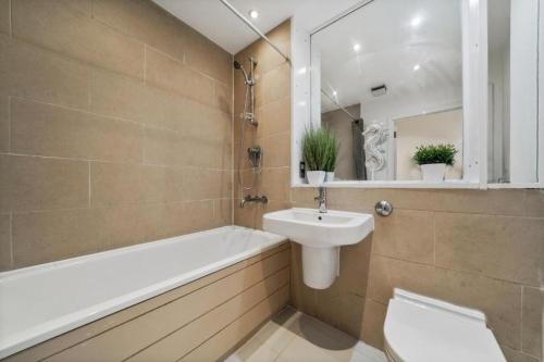 Modern1Bed Apartment London Camberwell Denmark Champion Hill في لندن: حمام مع حوض وحوض استحمام ومرحاض