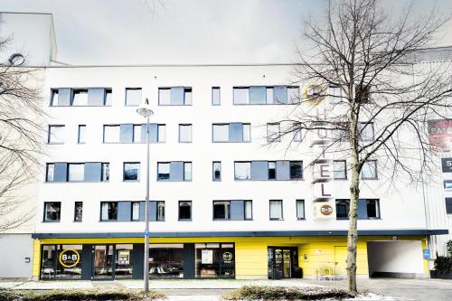 a large white building with a yellow front at B&B Hotel Bonn-West in Bonn