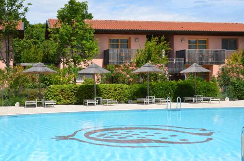 una piscina con sillas y sombrillas en un hotel en Green Village Eco Resort, en Lignano Sabbiadoro