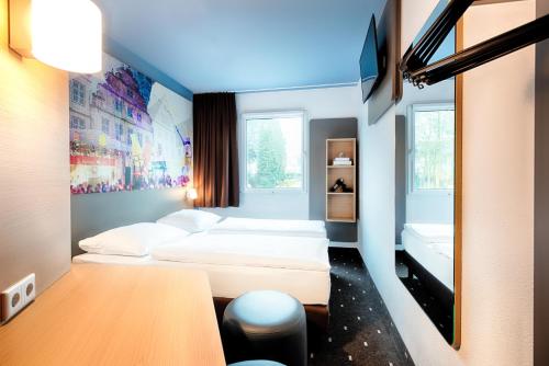 a room with two beds and a table in it at B&B Hotel Bielefeld-Ost in Bielefeld
