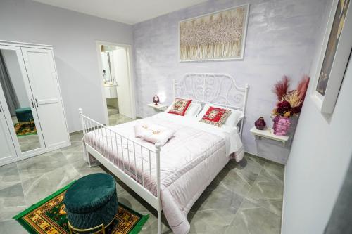 a bedroom with a white bed with a green stool at Piedigrotta Magique Luxury in Pizzo