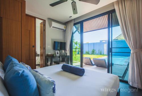 Two Bedroom Wings Pool Villa في شاطئ بانغ تاو: غرفة نوم بسرير ومنظر على فناء