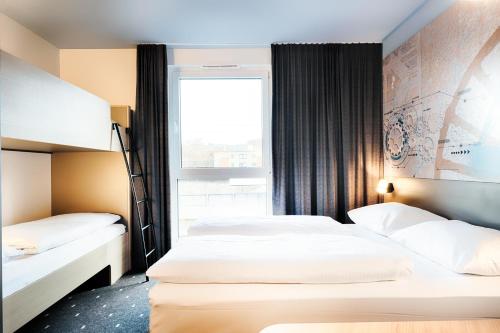 2 camas en una habitación de hotel con ventana en B&B Hotel Bochum-City en Bochum