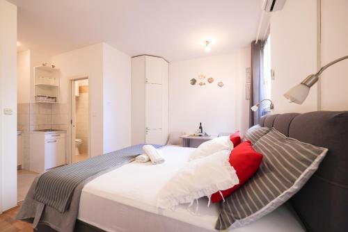 a bedroom with a bed with red and white pillows at Sea Organ Apartment 2 (Oldtown Studio) in Zadar