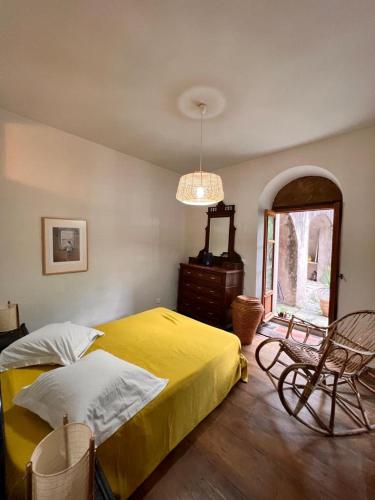 a bedroom with a yellow bed and a chair at Maison d'Americains Lapedina in Pietracorbara