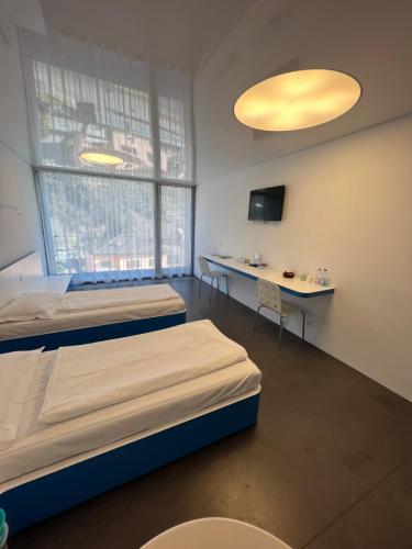 ein Krankenhauszimmer mit 2 Betten und einem Tisch in der Unterkunft Chromotel self check-in in Mezzovico