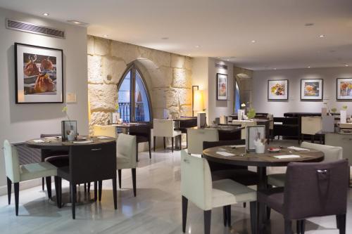 a restaurant with tables and chairs and a stone wall at Hospes Amérigo in Alicante