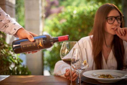 a man pouring a glass of wine in front of a woman at Agriturismo La Casa Degli Ospiti in Dolegna del Collio
