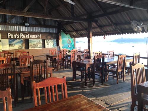 Muang Không的住宿－Pon's Riverside Guesthouse，大楼内的餐厅,配有木桌和椅子