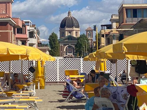 een groep mensen die in stoelen zitten onder gele paraplu's bij Centro storico, nuovo con terrazzo in Lido di Ostia