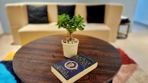 a table with a book and a potted plant on it at La vaccanza Suite -403 in Pune