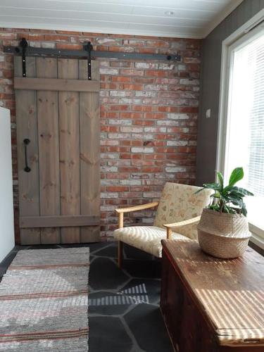 a living room with a chair and a brick wall at Alapihan Arboretumin vierasmaja ja sauna 