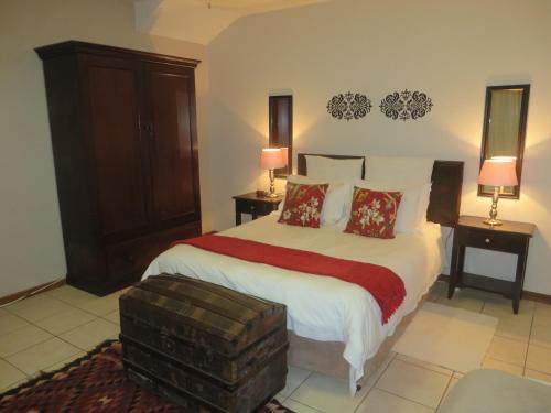 a bedroom with a large bed with two tables and two lamps at Rose and Ale Self Catering Units in Gonubie