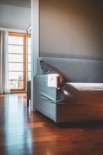 a couch sitting in a room with a wooden floor at Tre Merli Beach Hotel in Trieste