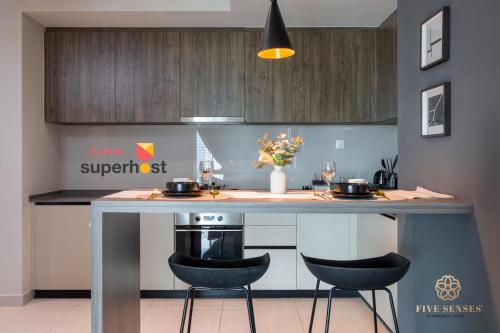 a kitchen with a counter with two stools at a kitchen island at Datum Jelatek Sky Residence KLCC, Five Senses in Kuala Lumpur