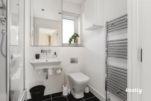 a bathroom with a sink and a toilet and a mirror at Puffin Way - Comfortable, spacious house with parking in Reading