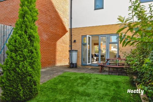 a yard with a bench in front of a building at Puffin Way - Comfortable, spacious house with parking in Reading
