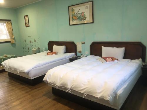 two beds in a room with white sheets at Bokelai B&B in Ren'ai