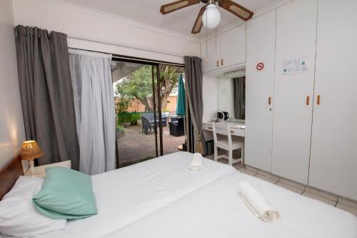 a bedroom with a bed and a window with a desk at Nothando Backpackers Lodge in Plettenberg Bay