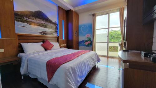 a bedroom with a bed and a large window at Holiday Hostel in Kenting