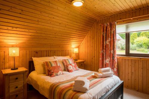een slaapkamer met een bed in een houten hut bij Thistle Lodges at Sandyhills Bay in Dalbeattie