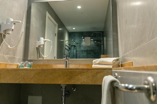 a bathroom with a sink and a large mirror at Hotel d'Or in Cala d´Or