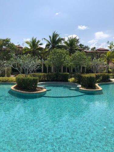 a swimming pool with blue water and palm trees at Laguna Luxury 2-Bed Pool Villa - Near Layan Beach in Layan Beach