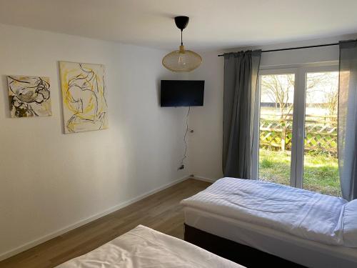 een slaapkamer met 2 bedden, een tv en een raam bij Monteurswohnung mit kleinem Garten 600M zur Stadtmitte in Siegen