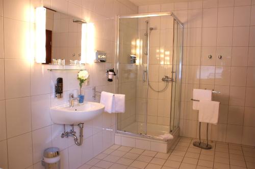 a bathroom with a glass shower and a sink at Hotel Altenwerder Hof in Hamburg