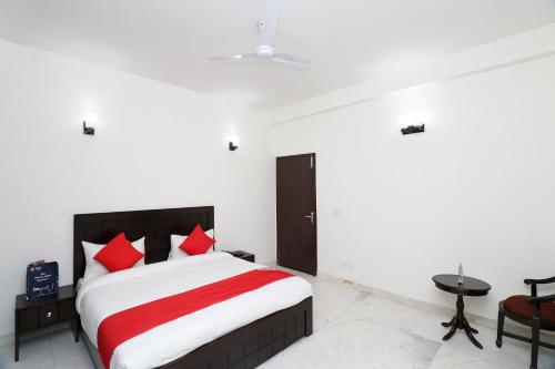 1 dormitorio con 1 cama grande con almohadas rojas en Super OYO The Primero Near Leisure Valley Park, en Gurgaon