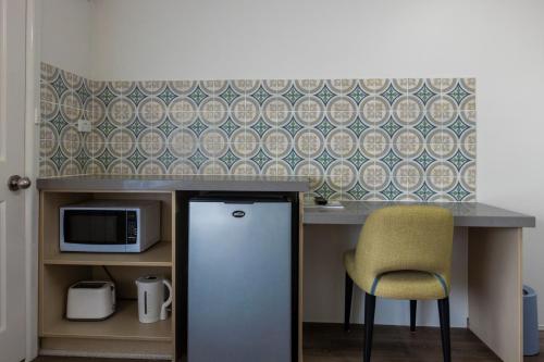 a kitchen with a counter with a refrigerator and a chair at Rosebud Motel in Tootgarook